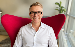 Frank Plümer mit weißem Hemd auf rotem Sessel